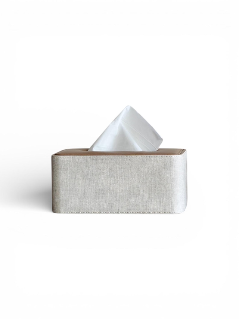 Rectangular PU leather tissue box cover with linen‑style beige texture and stitched wooden top, designed to fit standard Kleenex rectangular boxes. Features a modern, minimalist look that blends seamlessly with home décor styles from contemporary to boho. Durable magnetic closure allows easy tissue replacement, while the elegant design makes it perfect for bathroom, bedroom, living room, or office use. A stylish and functional home accessory or thoughtful gift idea.
