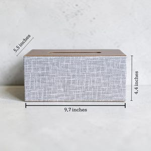 Rectangular PU leather tissue box cover with linen‑style beige texture and stitched wooden top, designed to fit standard Kleenex rectangular boxes. Features a modern, minimalist look that blends seamlessly with home décor styles from contemporary to boho. Durable magnetic closure allows easy tissue replacement, while the elegant design makes it perfect for bathroom, bedroom, living room, or office use. A stylish and functional home accessory or thoughtful gift idea.