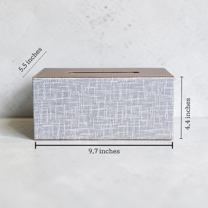 Rectangular PU leather tissue box cover with linen‑style beige texture and stitched wooden top, designed to fit standard Kleenex rectangular boxes. Features a modern, minimalist look that blends seamlessly with home décor styles from contemporary to boho. Durable magnetic closure allows easy tissue replacement, while the elegant design makes it perfect for bathroom, bedroom, living room, or office use. A stylish and functional home accessory or thoughtful gift idea.