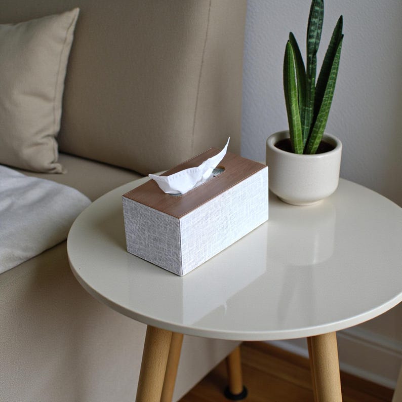 Rectangular PU leather tissue box cover with linen‑style beige texture and stitched wooden top, designed to fit standard Kleenex rectangular boxes. Features a modern, minimalist look that blends seamlessly with home décor styles from contemporary to boho. Durable magnetic closure allows easy tissue replacement, while the elegant design makes it perfect for bathroom, bedroom, living room, or office use. A stylish and functional home accessory or thoughtful gift idea.