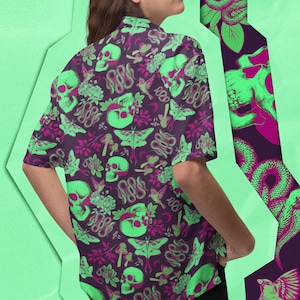 Könnte beinhalten: Ein dunkelviolettes Hemd mit Knöpfen und einem grün-rosa Druck von Totenköpfen, Schlangen, Schmetterlingen und Pilzen.