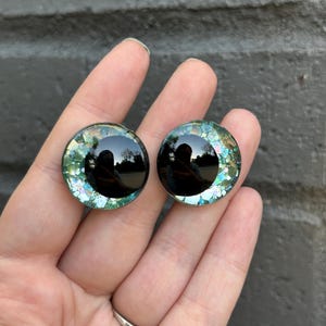 May include: Two black and green glitter doll eyes with a black pupil.