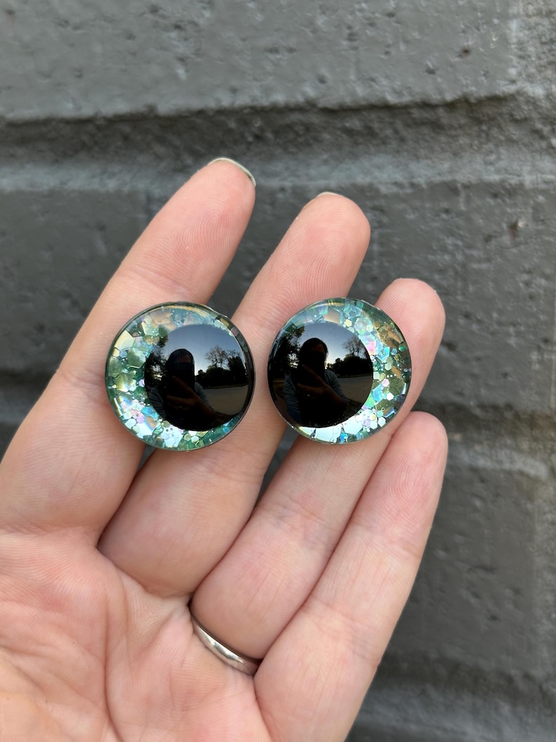 May include: Two black and green glitter doll eyes with a black pupil.