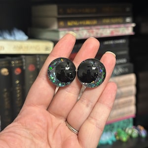 May include: Two black plastic doll eyes with iridescent green glitter embedded in the plastic.
