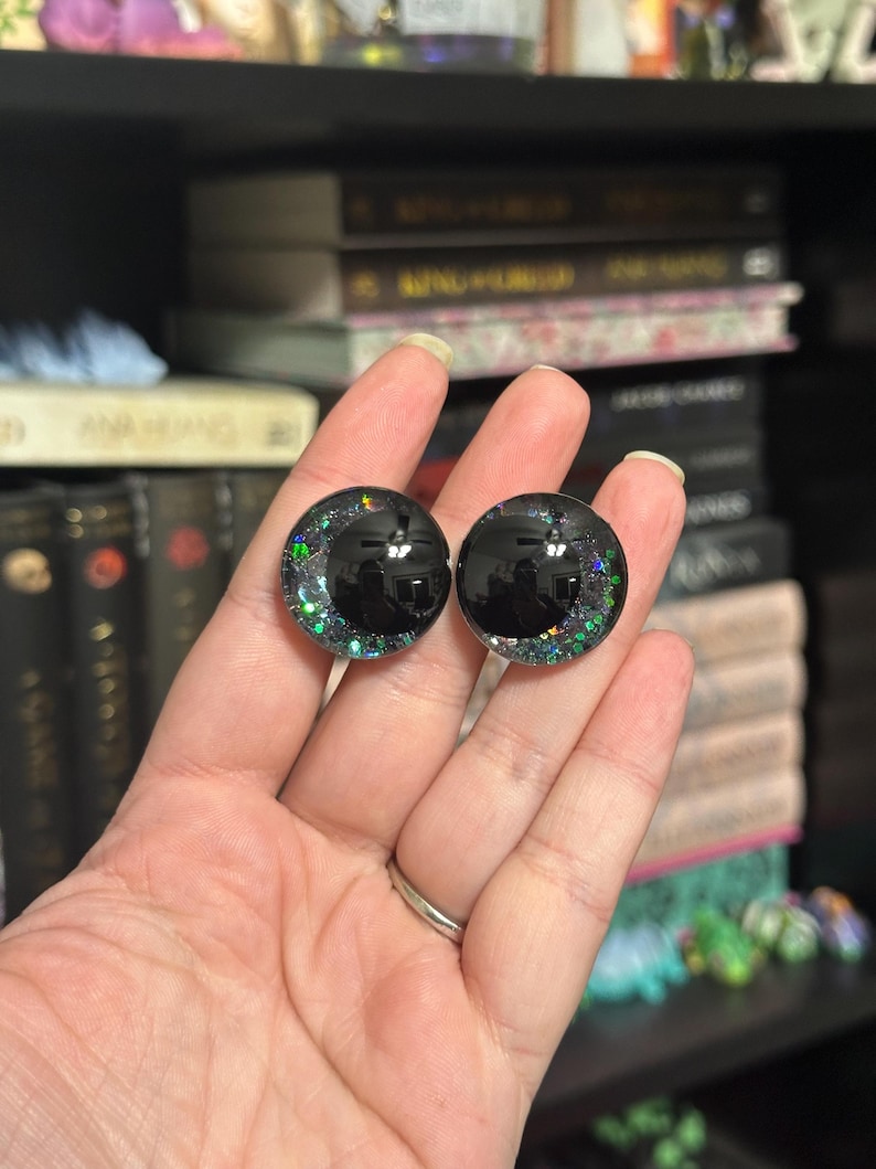May include: Two black plastic doll eyes with iridescent green glitter embedded in the plastic.