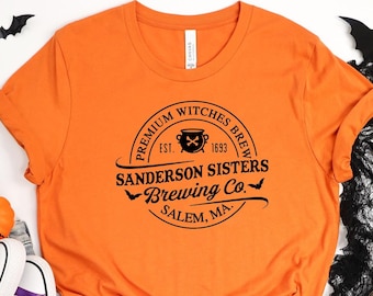 May include: Orange t-shirt with a black graphic of a vintage logo that reads "Premium Witches Brew Est. 1693 Sanderson Sisters Brewing Co. Salem, MA."