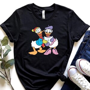 Daisy y Donald mirando un mapa, camiseta de Disney Donald y Daisy, camiseta de Disney Mickey y sus amigos, Navidad de Disney, camisetas de Navidad de Disney 2025