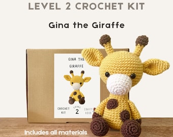 May include: A crocheted giraffe toy with brown spots, ears, and feet, and a white muzzle, sits next to a box labeled "Level 2 Crochet Kit" and "Gina the Giraffe." The box includes all materials and is made of 100% wool.