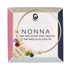 May include: Gold bangle bracelet with a charm that says "Remember Nonna We Love You". The charm has colorful crystals hanging from it. The bracelet comes in a box with the words "Nonna You have loved me ever since I was born, but I have loved you my entire life."