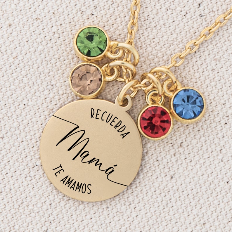 May include: Gold necklace with a round pendant that says "Recuerda Mam&aacute; Te Amamos". The pendant has five small colorful crystals attached to it.