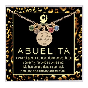 May include: A gold necklace with a charm that says "Recuerda abuelita te amamos" and a variety of colored crystals. The necklace is displayed in a black box with a leopard print background. The text "Abuelita" is written in large letters below the charm.