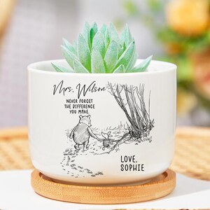 May include: White ceramic planter with a succulent plant. The planter features a black and white illustration of a bear and pig walking together, with the text "Mrs. Wilson, Never forget the difference you make. Love, Sophie."