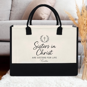 Peut inclure: Un sac fourre-tout noir et blanc avec un motif de croix et de couronne. Le texte dit "Sisters in Christ are sisters for life". Le nom "Kristen" est imprimé sous le texte.