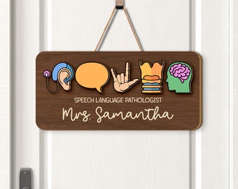 May include: A wooden sign with a brown background and colorful speech therapy symbols. The sign includes a hearing aid, speech bubble, hand sign, throat, and brain. Text on the sign reads "SPEECH LANGUAGE PATHOLOGIST" and "Mrs. Samantha".