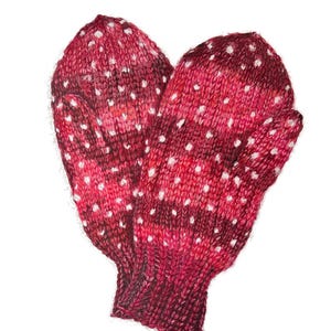 Puede incluir: Un par de guantes de punto rojos con lunares blancos. Los guantes están hechos de un material suave y cálido, perfectos para mantener las manos calientes en invierno.
