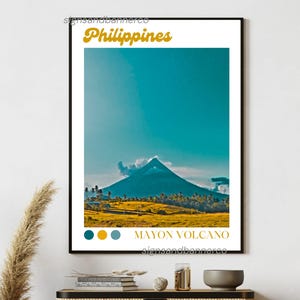 May include: A framed print featuring a vibrant landscape of the Philippines. The image showcases the Mayon Volcano under a bright blue sky. Text at the top reads "Philippines" and at the bottom "Mayon Volcano". The color palette includes teal, yellow, and brown.