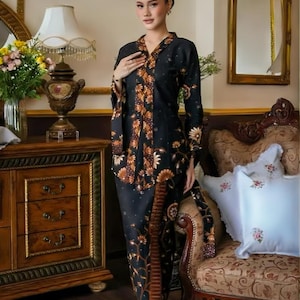 Puede incluir: Un vestido negro y marr&oacute;n con estampado floral y mangas largas. El vestido presenta un escote en V y una falda a juego. El atuendo lo lleva una persona en una habitaci&oacute;n con muebles antiguos y un espejo.