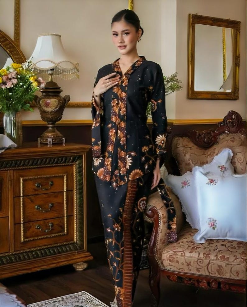 Puede incluir: Un vestido negro y marr&oacute;n con estampado floral y mangas largas. El vestido presenta un escote en V y una falda a juego. El atuendo lo lleva una persona en una habitaci&oacute;n con muebles antiguos y un espejo.