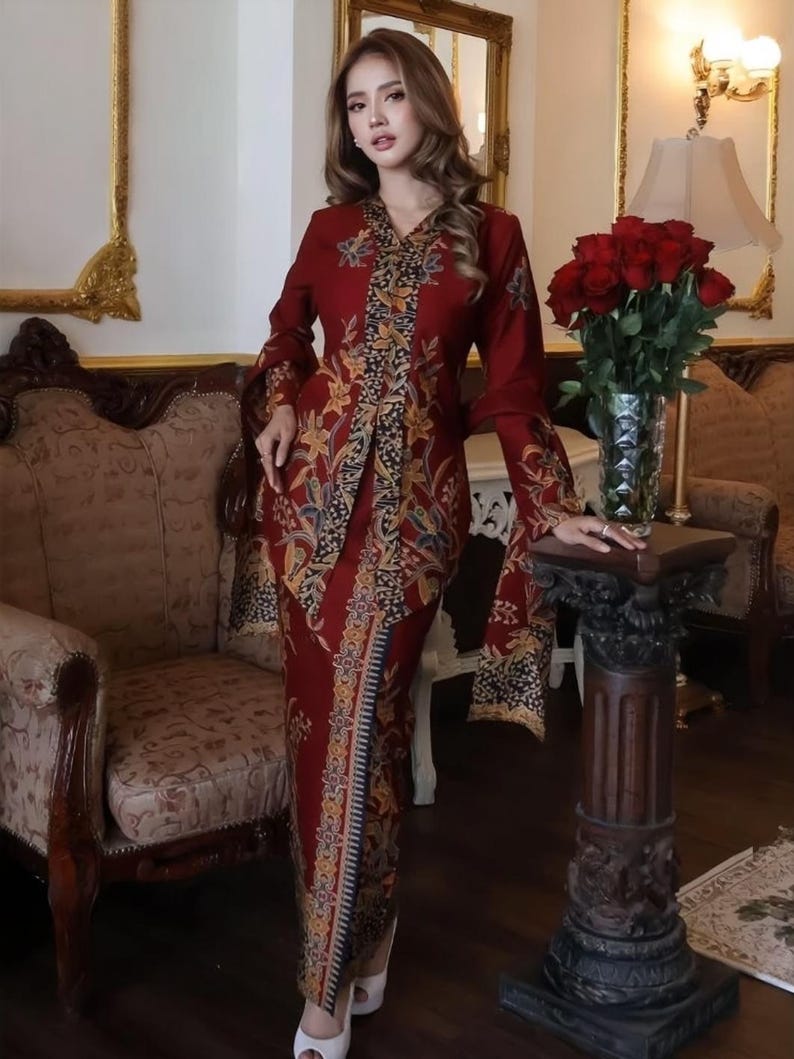 Puede incluir: Un vestido largo rojo con un estampado floral y mangas largas. El vestido tiene cuello en V y una abertura en la parte delantera. Las mangas son acampanadas en la mu&ntilde;eca. El vestido se usa con tacones blancos. El fondo incluye una silla, una mesa y un jarr&oacute;n con rosas rojas.