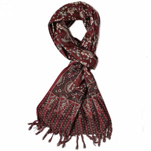 Puede incluir: Bufanda burdeos con un detallado estampado floral y geométrico. La bufanda tiene un borde con flecos y está anudada en el centro. El diseño incluye acentos blancos y grises, creando un textil visualmente rico.