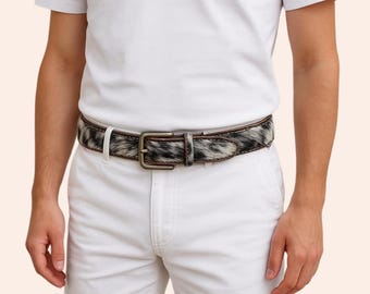 May include: A belt with a cowhide pattern in black, white, and gray, featuring a rectangular, antique-style buckle. The belt is worn with white shorts and a white t-shirt.