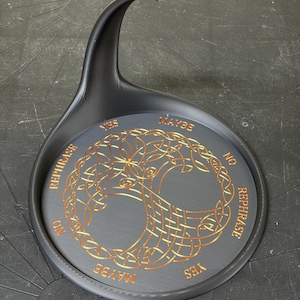 A black pendulum base features an intricate gold Tree of Life illustration surrounded by decision text against a workshop background.