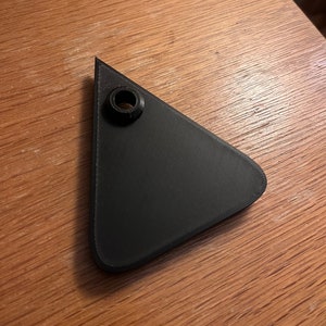 May include: A black triangular plastic object with a small hole in the center.