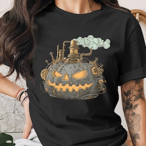 Könnte beinhalten: Schwarzes T-Shirt mit einem Steampunk-Kürbis-Design. Der Kürbis ist grau mit orangefarbenen, leuchtenden Augen und Mund, detailliert mit Zahnrädern und Rohren. Eine Wolke grünen Rauchs steigt auf und schafft ein einzigartiges Halloween-Thema.