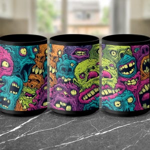 May include: Three black coffee mugs with a colorful, grotesque monster design. The mugs feature a repeating pattern of vibrant, cartoonish faces in shades of green, purple, blue, orange, and pink. The mugs are on a dark gray marble surface.