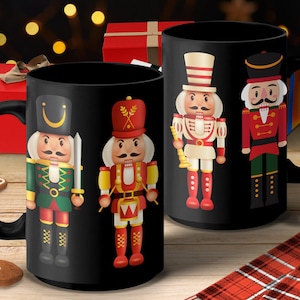 May include: Two black ceramic mugs with colourful nutcracker designs. One mug features a nutcracker in a green uniform holding a sword. The other mug has a nutcracker in a red uniform. Christmas-themed mugs.