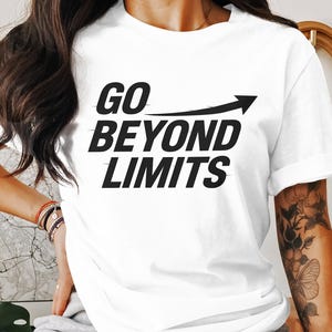 May include: White t-shirt featuring the phrase "GO BEYOND LIMITS" in black, with an upward-pointing arrow. The text is in a bold, sans-serif font. The t-shirt has a round neck and short sleeves, suitable for casual wear.