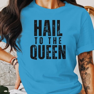 Könnte beinhalten: Ein hellblaues T-Shirt mit dem Aufdruck "HAIL TO THE QUEEN" in Schwarz.