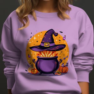 Puede incluir: Una sudadera lila con un diseño de Halloween. El gráfico muestra un sombrero de bruja morado sobre un caldero burbujeante con llamas, sobre un círculo naranja. Las calabazas y los frascos de pociones completan el diseño.