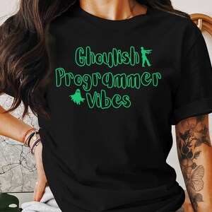 Op de afbeelding: Zwart t-shirt met de groene tekst "Ghoulish Programmer Vibes", versierd met een zombie en een spook. Dit casual T-shirt is ideaal voor programmeurs met een griezelig gevoel voor humor.