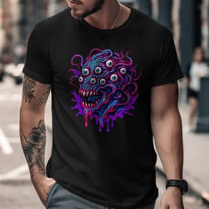 May include: Black t-shirt featuring a vibrant, multi-eyed monster design in shades of blue, purple, and pink. The graphic has a dripping effect, adding a dynamic element to the tee. The shirt is a classic crew neck.