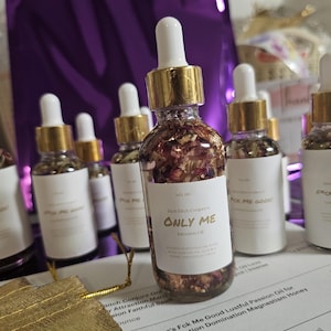 Könnte beinhalten: Eine Sammlung kleiner Glasflaschen mit goldenen Deckeln und Etiketten. Die Flaschen enthalten eine klare Flüssigkeit mit getrockneten Blumen und Kräutern. Die Etiketten lauten "Pick Me Good" und "Only Me".