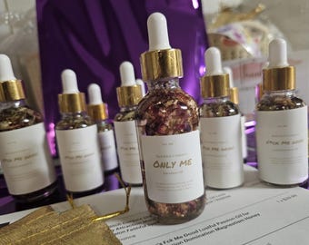 May include: A collection of small glass bottles with gold lids and labels. The bottles contain a clear liquid with dried flowers and herbs. The labels read "Pick Me Good" and "Only Me".