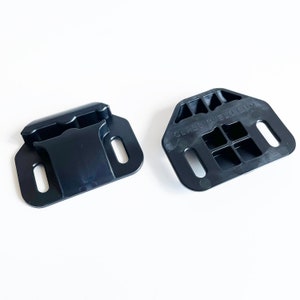 May include: Two black plastic bike rack mounts. The larger mount has the text "CLASSICVELO.COM" printed on it.