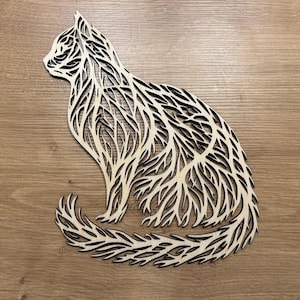 May include: A wooden cutout of a cat with a detailed, intricate design resembling branches and leaves. The cat is sitting with its tail curled around its body.