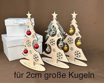 May include: Three wooden Christmas tree ornaments with cutouts of snowflakes. Each tree has a base and is designed to hold 2 cm ornaments. The trees are on a white surface with the text "für 2cm große Kugeln".