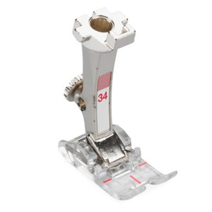 May include: A silver sewing machine foot with a clear plastic base. The foot has the number "34" printed on it.