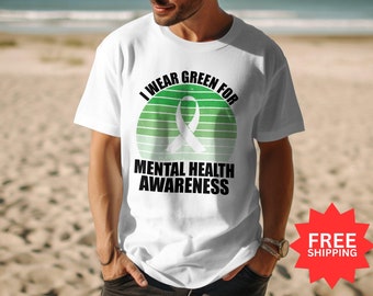 May include: White t-shirt with a green and white graphic of a ribbon and the text "I wear green for mental health awareness".