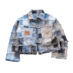 Pode incluir: Um casaco de ganga construído a partir de um patchwork de vários quadrados de tecido de ganga azul com bordas desfiadas. O casaco apresenta gola, mangas compridas, dois bolsos no peito e fechos de botões metálicos na frente e nos punhos.