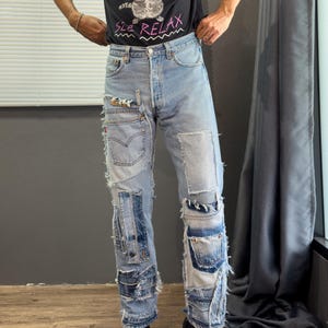 Può includere: Jeans in denim azzurro con un design patchwork caratterizzato da molteplici pannelli in tessuto sfrangiato, cuciture a vista e tasche in denim aggiuntive cucite sulle gambe. I jeans presentano una classica chiusura con bottoni e finitura.