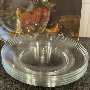May include: A stack of clear glass plates, likely for serving food, on a dark gray countertop.