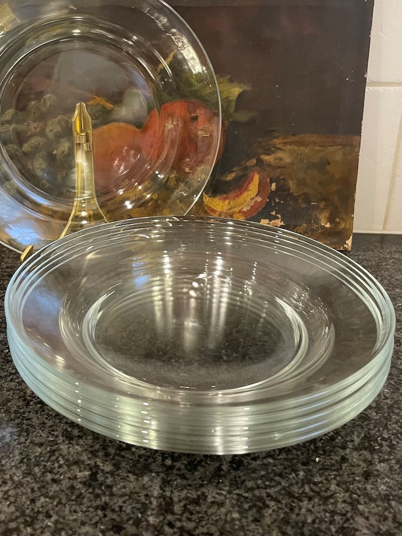 May include: A stack of clear glass plates, likely for serving food, on a dark gray countertop.