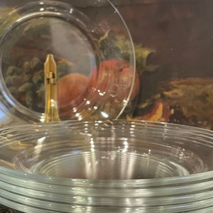 May include: A stack of clear glass plates, with a single plate on top that is slightly larger than the others.