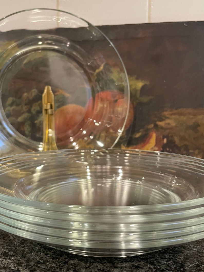 May include: A stack of clear glass plates, with a single plate on top that is slightly larger than the others.