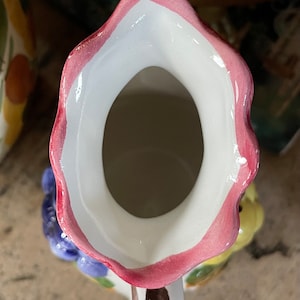 Puede incluir: Una jarra de cer&aacute;mica blanca con un borde rosa y un dise&ntilde;o floral. La jarra tiene una abertura ancha y un asa.