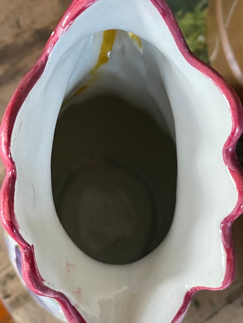 Puede incluir: El interior de una jarra de cer&aacute;mica con un esmalte blanco y un borde rosa. La jarra tiene un borde festoneado y un dise&ntilde;o floral.